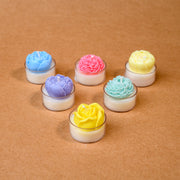 Colorful flower-shaped tealight candles arranged on a brown surface